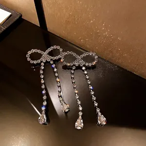 Gros plan sur des boucles d'oreilles nœud vintage avec glands en strass et gouttes