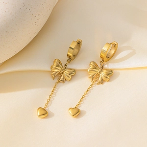 Elegante goldene Schleifen- und Herz-Ohrhänger Set auf Seidenhintergrund für Damen