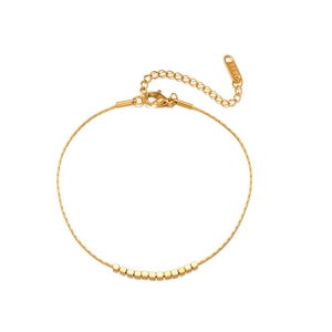 Detail of golden bracelet featuring small cube beads, lobster clasp, and K18 tag