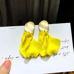 Gros plan détaillé de boucles d'oreilles pétales de fleurs en résine jaune sur carte blanche.