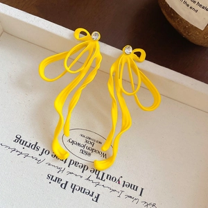 Gros plan de boucles d'oreilles ruban jaune vif avec clous en cristal étincelants