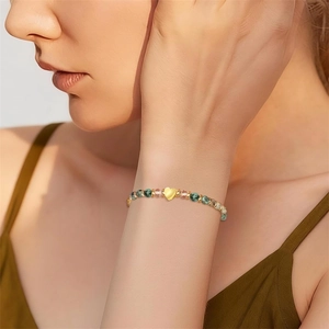 Close-up view of a 4mm natural stone bracelet with a golden heart charm on woman wrist