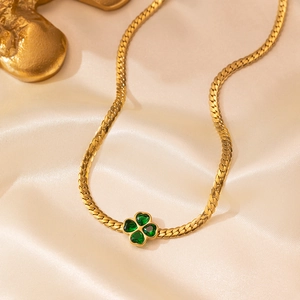 Golden emerald four-leaf clover heart pendant necklace on luxury champagne silk fabric