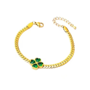 Detail of flat gold-plated chain bracelet with green heart-shaped four-leaf clover pendant