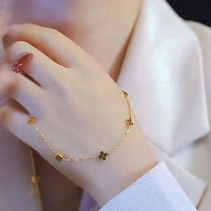 Elegant gold four-leaf clover necklace with small cubic charms on a thin chain link