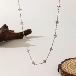 Detailed view of silver clover and square charms on a slim stainless steel necklace