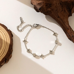 Detailed macro view of silver clover charms and cubic beads on a stainless steel chain