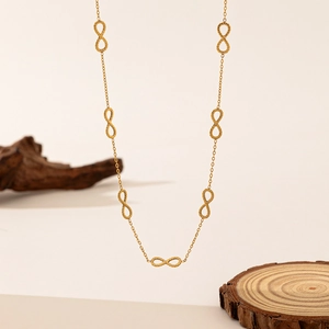 Golden infinity symbol necklace with textured charms on rustic wooden display