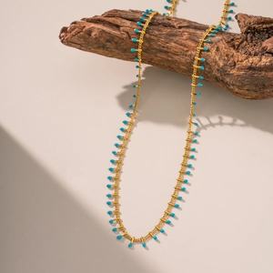 Gold long necklace with blue turquoise teardrop pendants on a natural wood branch