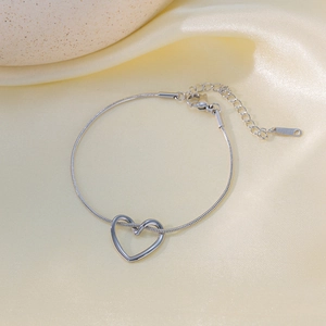 Minimalist silver stainless steel heart bracelet with snake chain on silk background