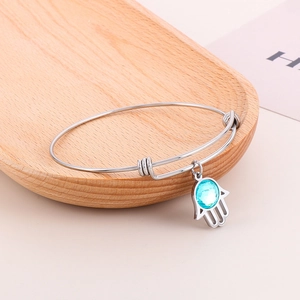 Minimalist adjustable stainless steel Hamsa hand bangle featuring a vibrant blue crystal charm
