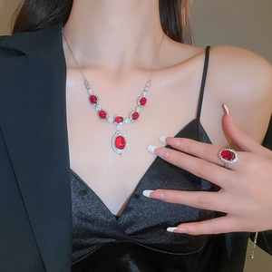 Primer plano de un elegante collar con colgante de resina roja y un anillo a juego