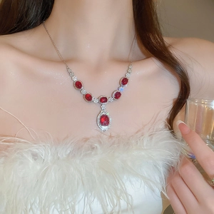 Primer plano de un collar vintage con colgantes rojos ovalados y circonitas para mujer
