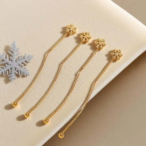 Elegant gold clover leaf dangle earrings with delicate chains on soft beige velvet background