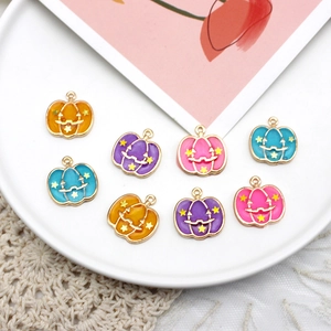 Close-up of colorful Halloween pumpkin charms with enamel stars and smiley faces on a plate.