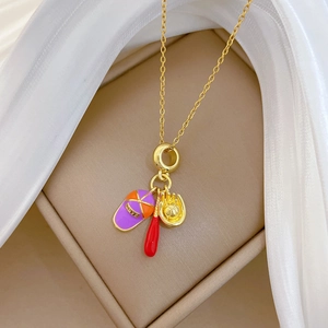 Gros plan de collier avec pendentifs baseball, chapeau en émail violet et batte rouge