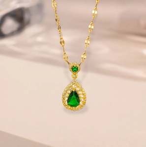 Elegant gold chain necklace featuring a pear-cut emerald green pendant with halo crystals