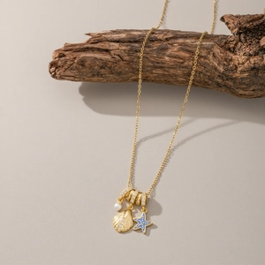 Gold shell and blue starfish pendant necklace with pearls on a minimalist wooden branch