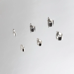 Makroaufnahme von silbernen Tropfenkrallenfassungen für Schmuck-DIY auf Reflexionsfläche.