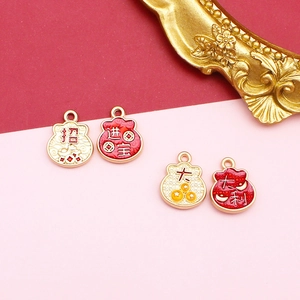 Close-up view showing the intricate red and gold enamel patterns on lucky pouch charms