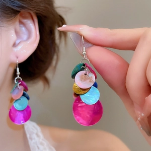 Gros plan de boucles d'oreilles pendantes en nacre ronde multicolore sur crochets en argent.