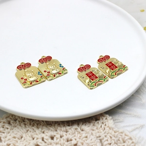 Detail view of red and gold Chinese lucky cat and peace charms for DIY jewelry
