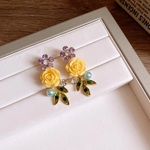 Vue détaillée des boucles d'oreilles rose en résine jaune avec cristaux violets