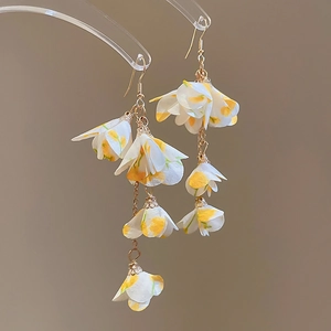 Détail de boucles d'oreilles multicouches en fleur de résine jaune avec crochets dorés