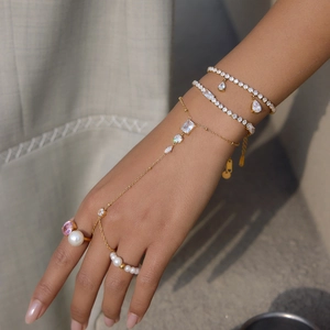 Detailweergave van elegante gouden handketting en gestapelde zirkonia armbanden aan de hand