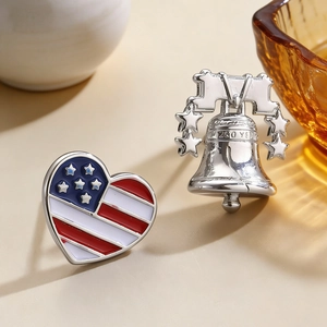 Close-up of USA 250th anniversary pins including a heart flag and a silver liberty bell