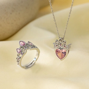 Macro shot of silver crown jewelry set with pink heart stone necklace and ring