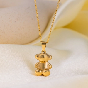 Polished golden 3D bear pendant necklace with delicate chain on soft fabric background