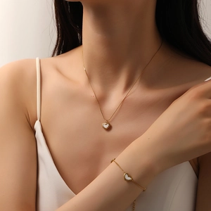 Gold stainless steel jewelry set with shell heart necklace and bracelet on female model
