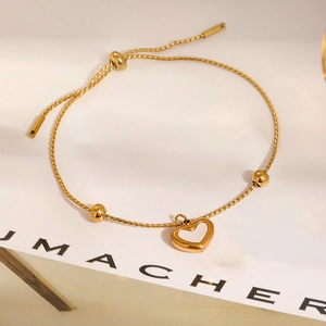 Detail of adjustable gold heart anklet with polished beads on minimalist display card