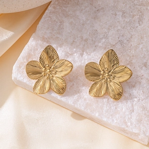 Elegant gold flower stud earrings with brushed metal texture on champagne silk