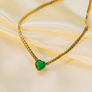 Detail einer Vintage-Herz-Halskette mit grünem Zirkon-Anhänger an goldener Schlangenkette