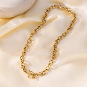 Golden chunky chain necklace with OT toggle clasp on cream silk fabric background