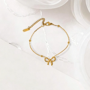 Élégant collier en acier inoxydable doré avec pendentif nœud et accents de perles