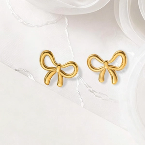 Boucles d'oreilles nœud dorées avec design élégant sur fond de tissu blanc texturé