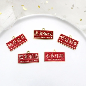 Close-up of red enamel DIY pendants with Chinese blessing phrases and gold trim