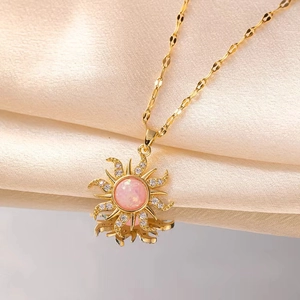Elegant gold sunburst pendant necklace with pink opal and zircon on champagne silk fabric