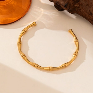 Minimalist knot 18K gold plated titanium steel open bangle on marble surface