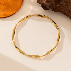 Close-up of a 18K gold-plated stainless steel knotted bracelet with twisted metal texture