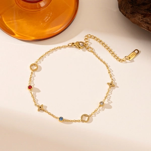 Detail shot of golden titanium steel bracelet featuring clovers and colorful stones.
