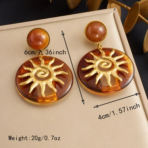 Detail of amber sunburst pendant earrings on leather display with dried floral accents