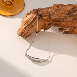 Close-up of a silver eggplant-shaped curved pendant on a sleek snake chain necklace