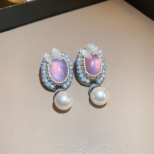 Detail view of elegant purple gem earrings with butterfly accents and pearl drops