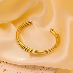 Close-up of 18K gold-plated double-layer crossover open bangle on satin silk background