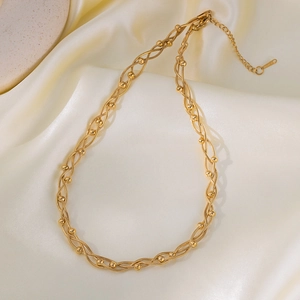 Minimalist multi-layered gold stainless steel chain necklace with beads on silk background