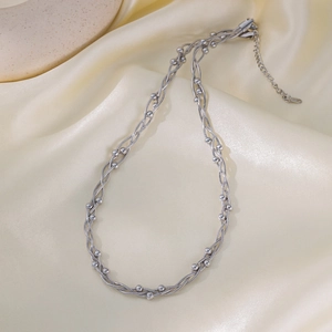 Silver multi-layer beaded chain necklace in stainless steel on a champagne silk background